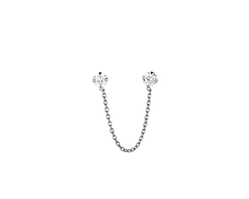 Puede incluir: Un par de pendientes de plata con un peque&ntilde;o diamante en cada extremo conectado por una cadena de plata.