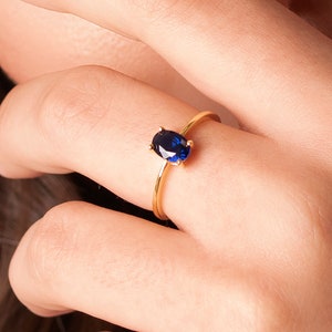 May include: A gold ring with a blue oval-shaped gemstone.