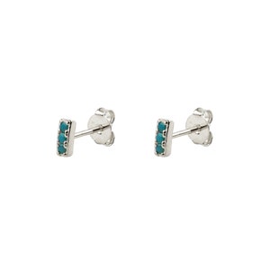May include: A pair of silver stud earrings with a small turquoise bar set with five turquoise stones.