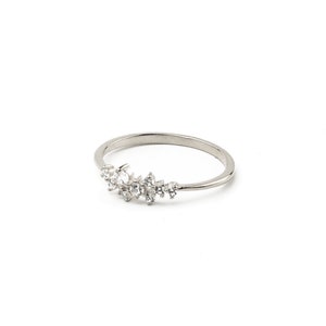 May include: A silver ring with a cluster of small, clear stones set in a crescent shape.