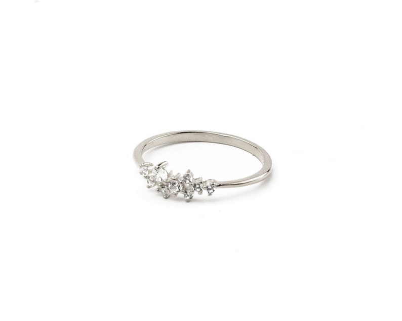 May include: A silver ring with a cluster of small, clear stones set in a crescent shape.
