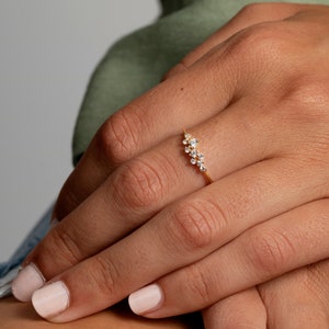 May include: A gold ring with a curved line of small, clear stones.