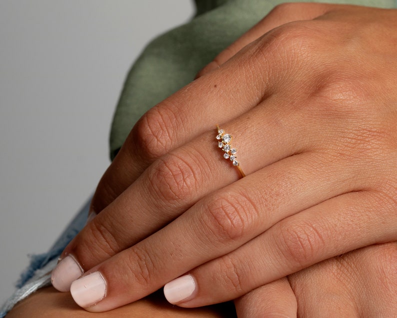 May include: A gold ring with a curved line of small, clear stones.