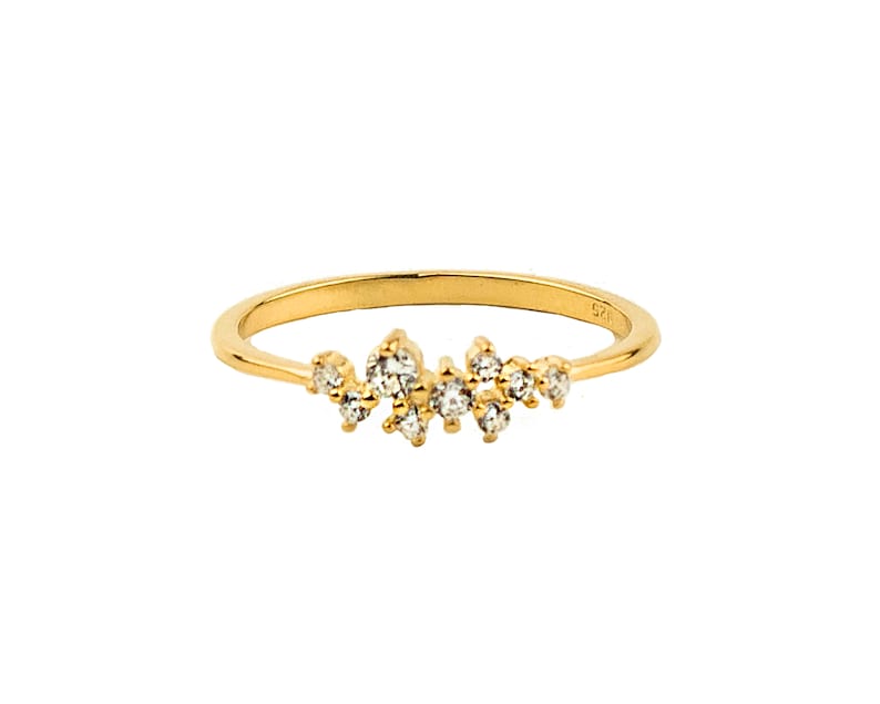 May include: A delicate gold band ring with a cluster of small, clear diamonds set in a random pattern along the top of the band.