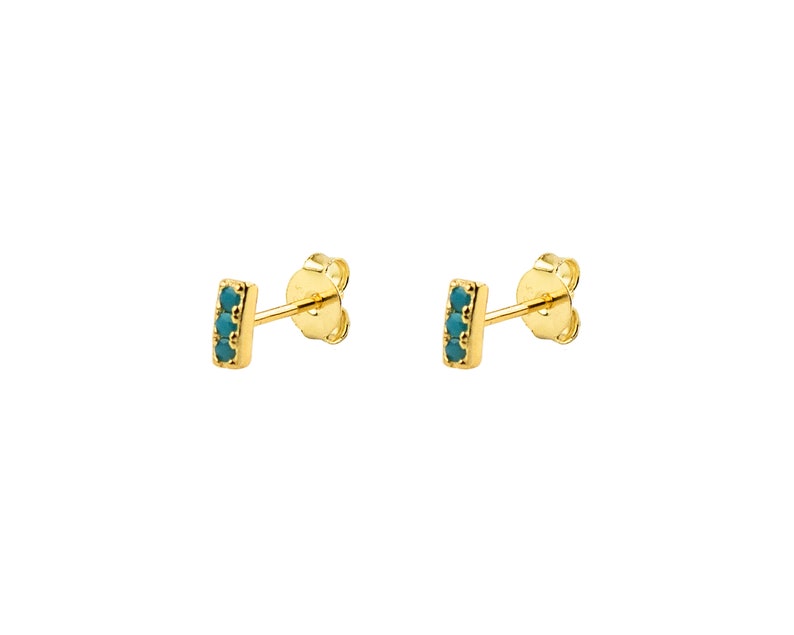 May include: Gold stud earrings with a row of turquoise stones.
