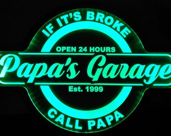 Peut inclure: Enseigne au néon verte avec le texte "If it's broke, Papa's Garage, Open 24 Hours, Est. 1999, Call Papa" dans un cercle.