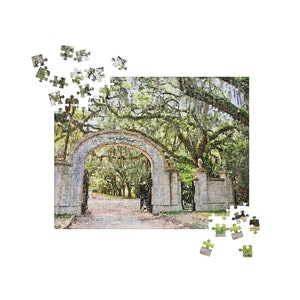 May include: A stone archway with the words "1775  Wormsloe  2012" inscribed above the arch. The archway is surrounded by lush green trees and leads to a path.