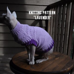 May include: A Sphynx cat wearing a lavender-colored knitted sweater with a purple trim. The sweater has a textured design and is labeled "KNITTING PATTERN 'LAVENDER'" in white text. The cat is sitting on a round wooden table.