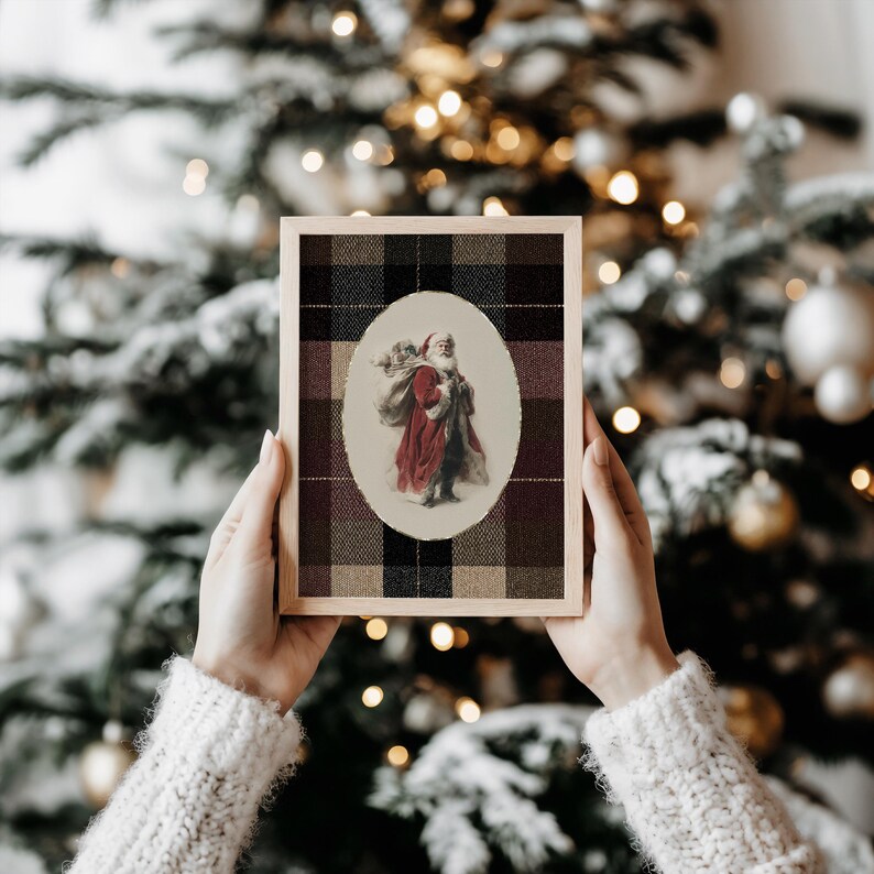 May include: A framed Christmas print featuring an oval image of Santa Claus carrying a sack. The print is set against a plaid background in shades of black, brown, and burgundy, with a wooden frame.