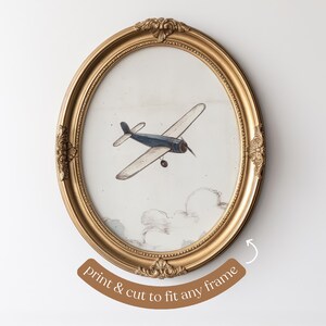 May include: An oval, gold-colored frame surrounds a vintage-style print of a biplane in flight. The biplane is blue and beige, set against a cloudy sky. The text "print & cut to fit any frame" is at the bottom.