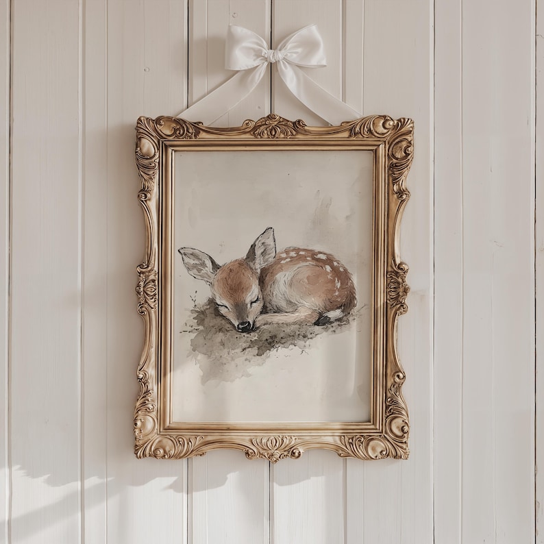 May include: A framed watercolour painting of a sleeping fawn with brown and white fur. The frame is gold with ornate details.