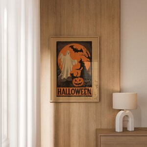 K&ouml;nnte beinhalten: A framed Halloween poster with a ghost, witch, black cat, and pumpkin against an orange moon. The word "HALLOWEEN" is printed in orange block letters. The poster is displayed on a wooden wall.