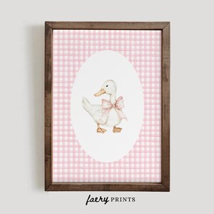 Puede incluir: Un pato blanco con un lazo rosa se presenta sobre un fondo de cuadros vichy rosa y blanco. El pato est&aacute; en un marco ovalado blanco.