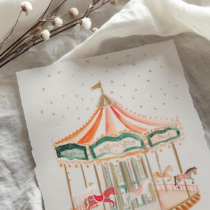 May include: A watercolour painting of a vintage carousel with a red, orange and green striped canopy. The carousel has white horses and a gold base. The background is a light blue with white dots.