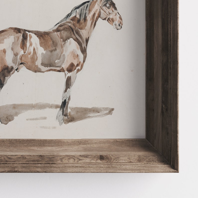 K&ouml;nnte beinhalten: Ein gerahmtes Aquarellbild eines braunen und wei&szlig;en Pferdes, das auf einem wei&szlig;en Hintergrund steht. Der Rahmen ist aus Holz mit brauner Beize.