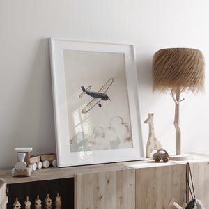 May include: A framed print of a vintage airplane in flight, with a blue and white color scheme. The artwork is displayed on a wooden cabinet, alongside a wooden giraffe, car, and a tree-shaped lamp with a textured lampshade. The scene evokes a nursery or children's room.