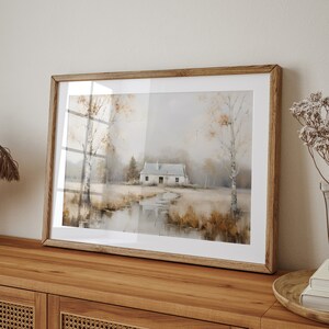 May include: A framed watercolor painting of a white cottage in a misty landscape with trees and a reflection of the cottage in a pond. The painting is in a light wood frame.