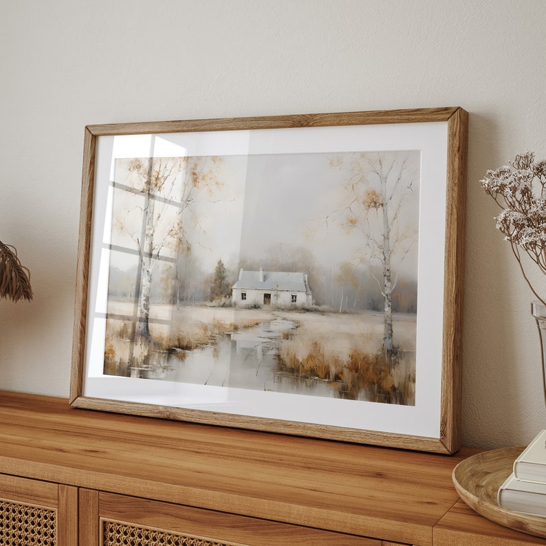 May include: A framed watercolor painting of a white cottage in a misty landscape with trees and a reflection of the cottage in a pond. The painting is in a light wood frame.