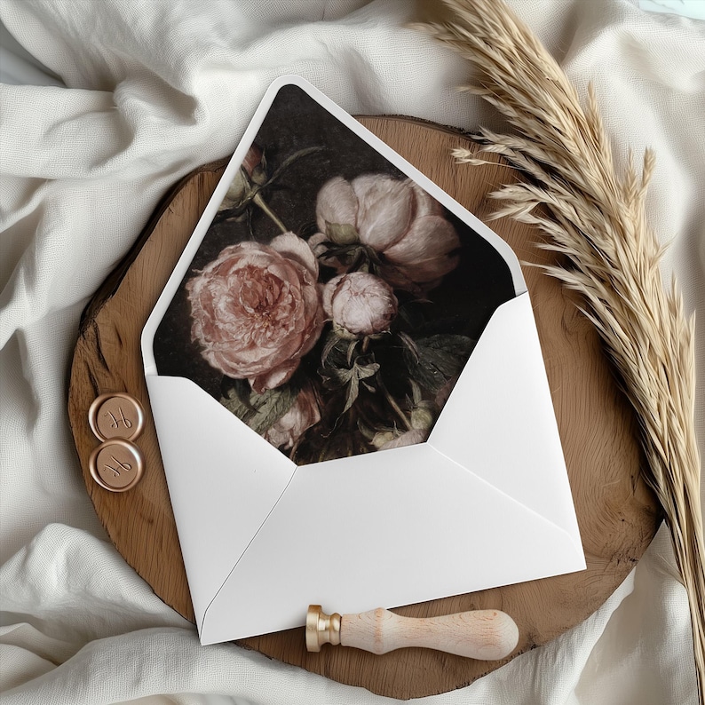 May include: A white envelope with a floral design on the front. The design features a bouquet of pink and white roses with dark green leaves. The envelope is on a wooden surface with two wax seals.