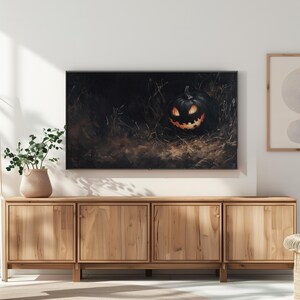 May include: A wooden entertainment center with three drawers and three doors. The center is in a living room with a television displaying a dark image of a jack-o-lantern.