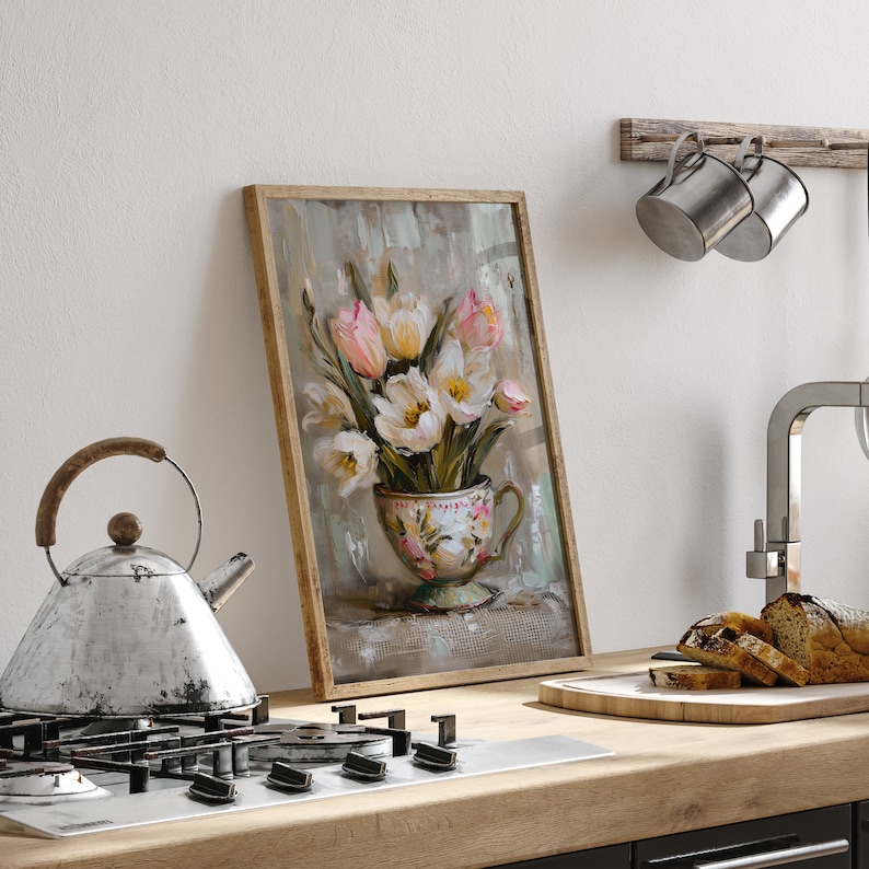 May include: A framed painting of a bouquet of white and pink tulips in a vintage teacup. The painting has a textured background and is set against a white wall.