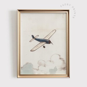 May include: A framed vintage-style print featuring a blue and cream-colored airplane soaring above sketched clouds. The artwork has a gold frame and the text "FAERY PRINTS" is printed on the top right corner.