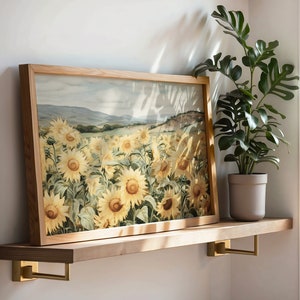 May include: A framed print of a field of sunflowers in shades of yellow and brown. The print is hanging on a wooden shelf with a potted plant in the background.
