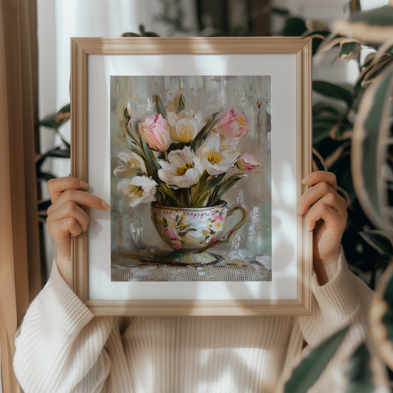 May include: A framed painting of a bouquet of white and pink tulips in a vintage teacup. The tulips are arranged in a vase with green leaves and are painted in a realistic style.