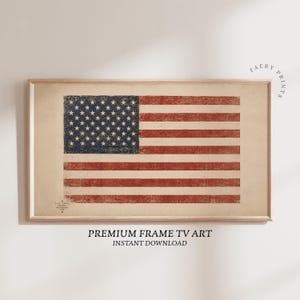May include: A rectangular framed print featuring a distressed, vintage-style American flag with a dark blue canton of white stars and horizontal red and white stripes on a beige background. Small text is visible in the lower left corner.