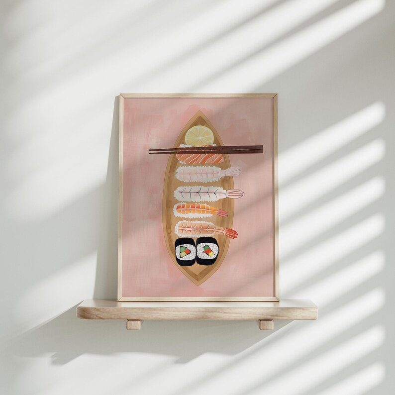 May include: A framed illustration of a pink background with a wooden boat filled with sushi. The boat contains shrimp, avocado, and cucumber sushi rolls, as well as two maki rolls. A lemon wedge is visible in the boat. Two chopsticks are placed on top of the boat.