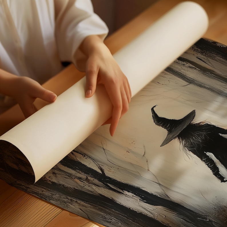 May include: A black and white illustration of a witch with a pointed hat and long flowing robes, printed on a white canvas. The canvas is being rolled up by a person's hand.