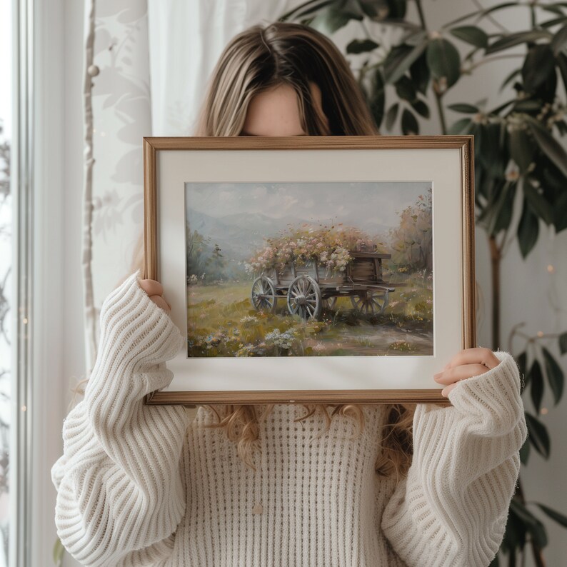 May include: A framed painting of a horse-drawn wagon filled with flowers, set against a backdrop of a lush green meadow and a distant mountain range. The painting is in a rustic wooden frame.
