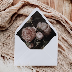 May include: A white envelope with a floral design on the front. The design features pink peonies on a dark background.