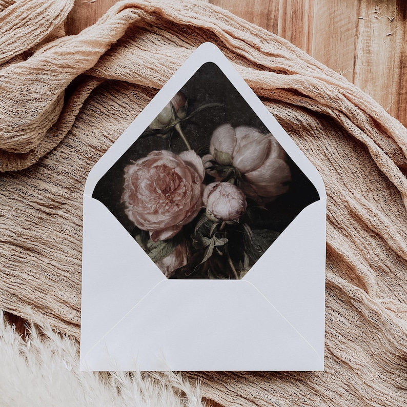 May include: A white envelope with a floral design on the front. The design features pink peonies on a dark background.