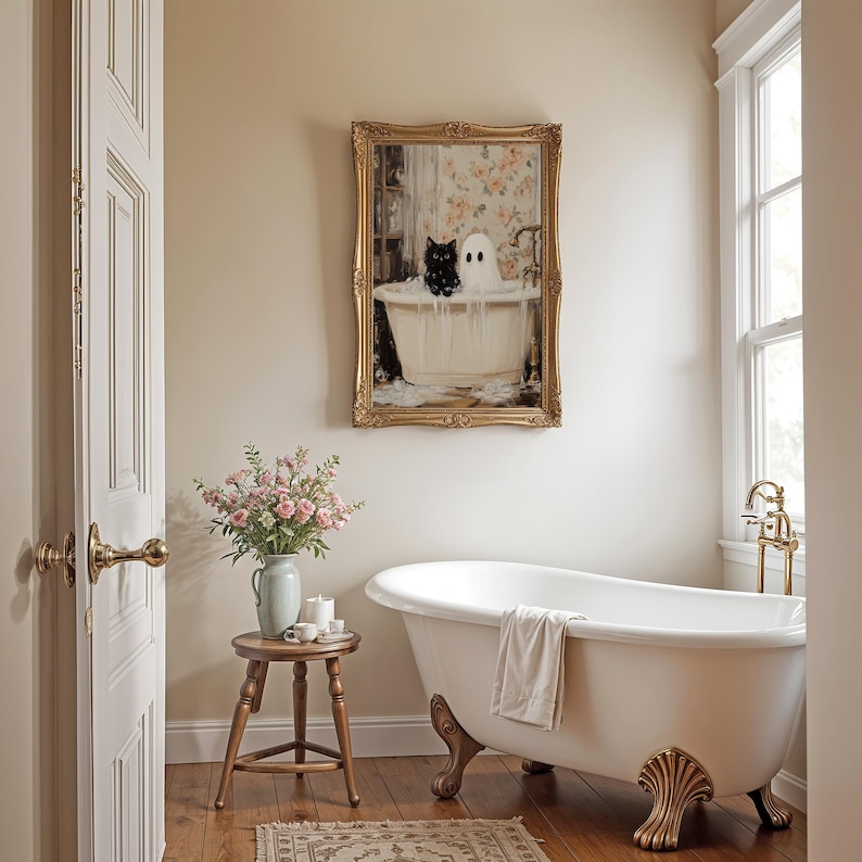 May include: A white clawfoot bathtub with a towel draped over the edge, a small wooden stool with a vase of pink flowers, and a framed painting of a black cat and a white ghost in a bathtub. The painting is in a gold frame and has a floral background.