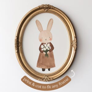 May include: A printable art print featuring a brown bunny holding a bouquet of white flowers. The bunny is wearing a brown dress and is standing on a white background. The print is framed in a gold oval frame.