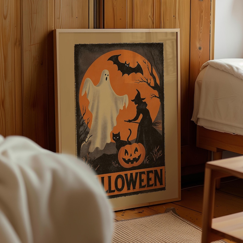 K&ouml;nnte beinhalten: Gerahmtes Halloween-Poster mit einem Geist, einer Hexe, einer schwarzen Katze und einem K&uuml;rbis vor einem orangefarbenen Mond. Das Wort "HALLOWEEN" ist unten in Orange gedruckt. Das Kunstwerk befindet sich in einem Holzrahmen und lehnt an einer Holzwand.