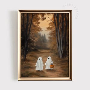 May include: A framed art print depicting two white ghost figures standing on a dirt path within a forest of tall brown trees. One ghost holds a small orange jack-o'-lantern bucket. The scene features a soft, warm, autumnal color palette.