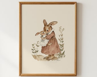May include: A framed watercolor print featuring two brown rabbits. One larger rabbit in a brown dress holds a smaller rabbit wearing a white dress. The artwork has a vintage aesthetic with soft colors and botanical accents.