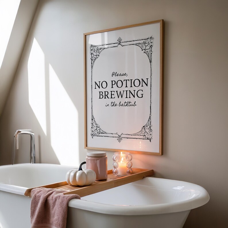 May include: A framed print with the text "Please, NO POTION BREWING in the bathtub" hangs above a white bathtub. A wooden tray holds a candle, a small pumpkin, and a pink jar. A pink towel rests on the tray.