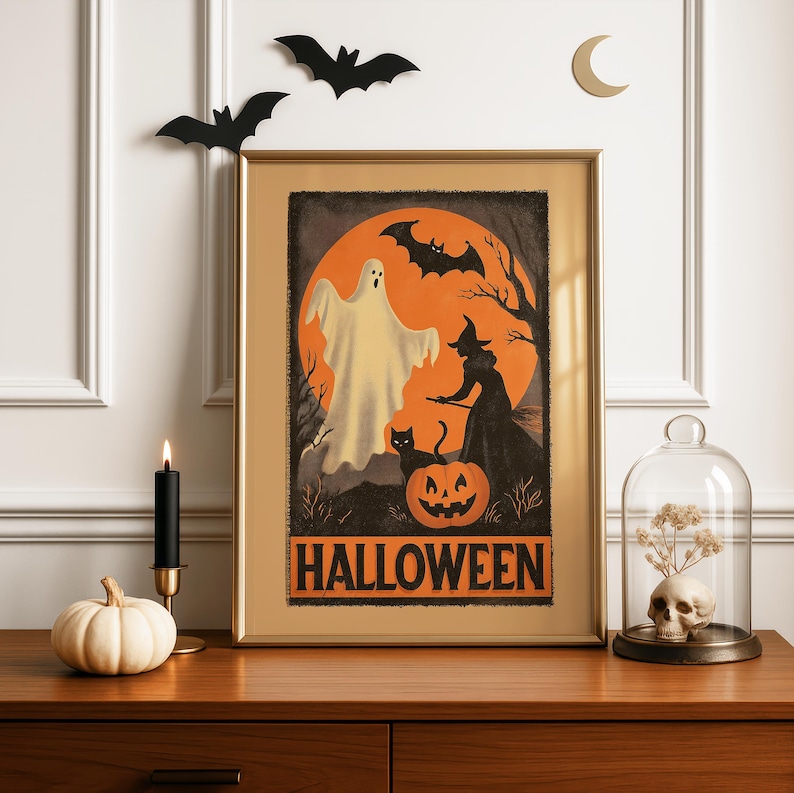 K&ouml;nnte beinhalten: Ein gerahmtes Halloween-Poster mit Vintage-Design. Das Kunstwerk zeigt einen Geist, eine Hexe, eine schwarze Katze und einen K&uuml;rbis vor einem orangefarbenen Mond. Das Wort "HALLOWEEN" ist fett gedruckt. Dekorative Flederm&auml;use, eine Kerze und ein K&uuml;rbis befinden sich auf einer Holzoberfl&auml;che.