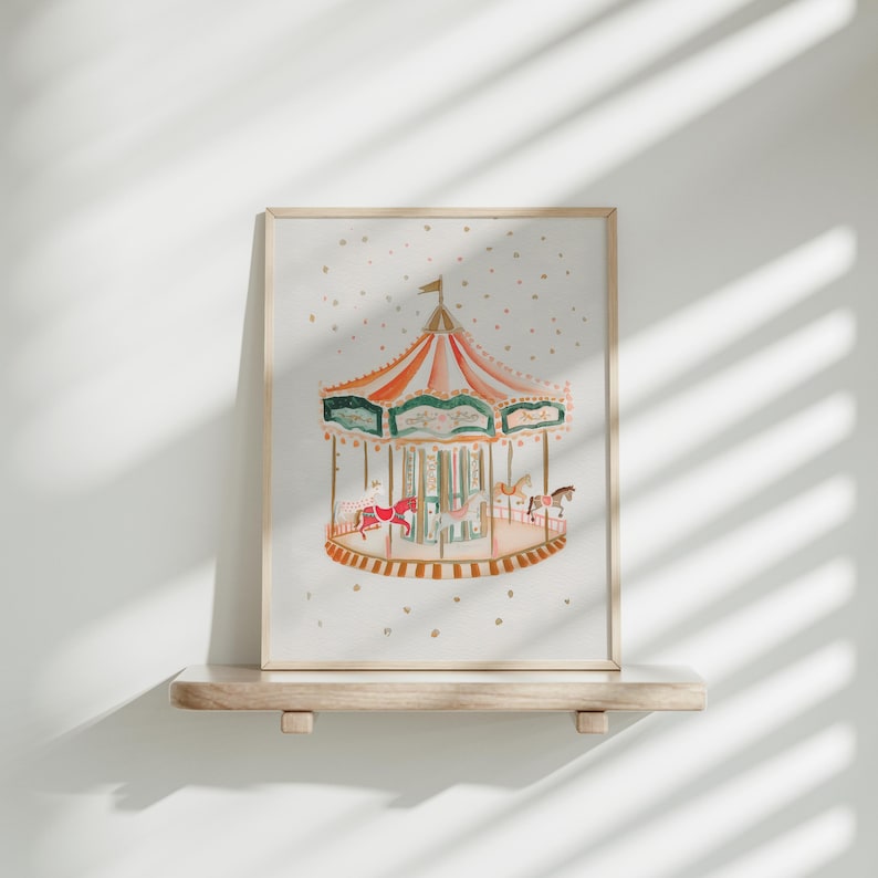 May include: A framed watercolour painting of a vintage carousel with colourful horses and a gold trim. The carousel is set against a white background with gold glitter.