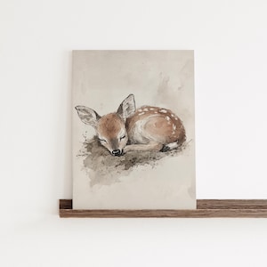 May include: A watercolour painting of a fawn sleeping on a bed of leaves. The fawn is brown with white spots and has its eyes closed. The background is a light brown colour.