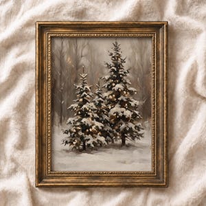 May include: A framed oil painting depicting two snow-covered evergreen trees in a winter forest setting. The artwork features a muted colour palette of white, grey, and brown tones, enclosed within an ornate, antique-style metallic gold frame.