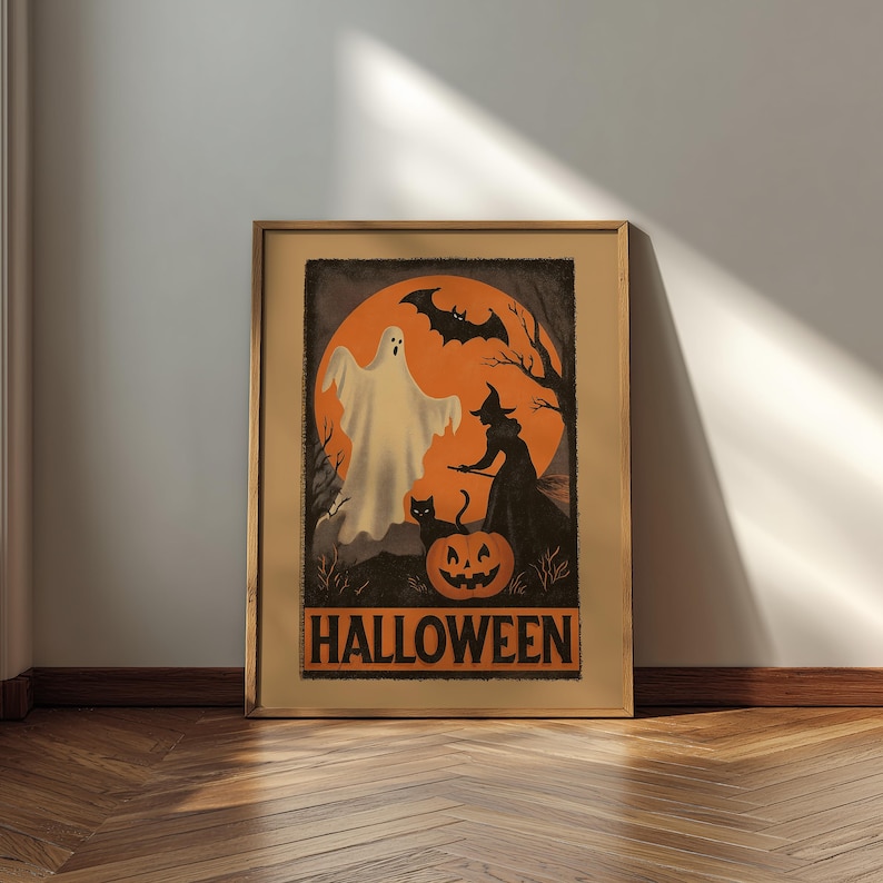 K&ouml;nnte beinhalten: Ein gerahmter Halloween-Druck mit einem Geist, einer Hexe, einer schwarzen Katze und einem K&uuml;rbis vor einem orangefarbenen Hintergrund. Das Wort "HALLOWEEN" steht in orangefarbenen Blockbuchstaben. Das Kunstwerk befindet sich in einem Holzrahmen.