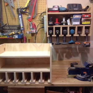 May include: A wooden storage shelf with two shelves and multiple compartments for organizing tools. The shelf is made of light-colored wood and has a simple design. It is sitting on a wooden table next to a blue metal vise.