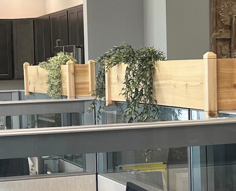 May include: Two wooden planter boxes with green plants hanging over the edge. The boxes are mounted on a wall and are made of natural wood.