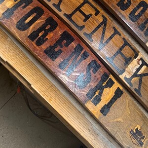 May include: Four wooden signs with black painted lettering. The signs read "WARSOW", "KRENEK", "STOREMSK", and "WEINSK" with a small logo on the bottom right sign.