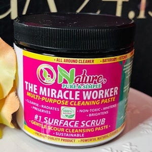 May include: A pink and green jar of all-natural multi-purpose cleaning paste labeled "The Miracle Worker" by "Onature, Pure & Simple". The jar is labeled as a #1 Surface Scrub and a gentle scour cleansing paste. The jar is 100% natural, non-toxic, and sustainable.