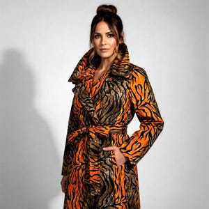 May include: A long coat featuring an orange and black tiger stripe pattern. The coat has a wide collar, a matching belt, and a pocket. The fabric is patterned with a striking animal print.